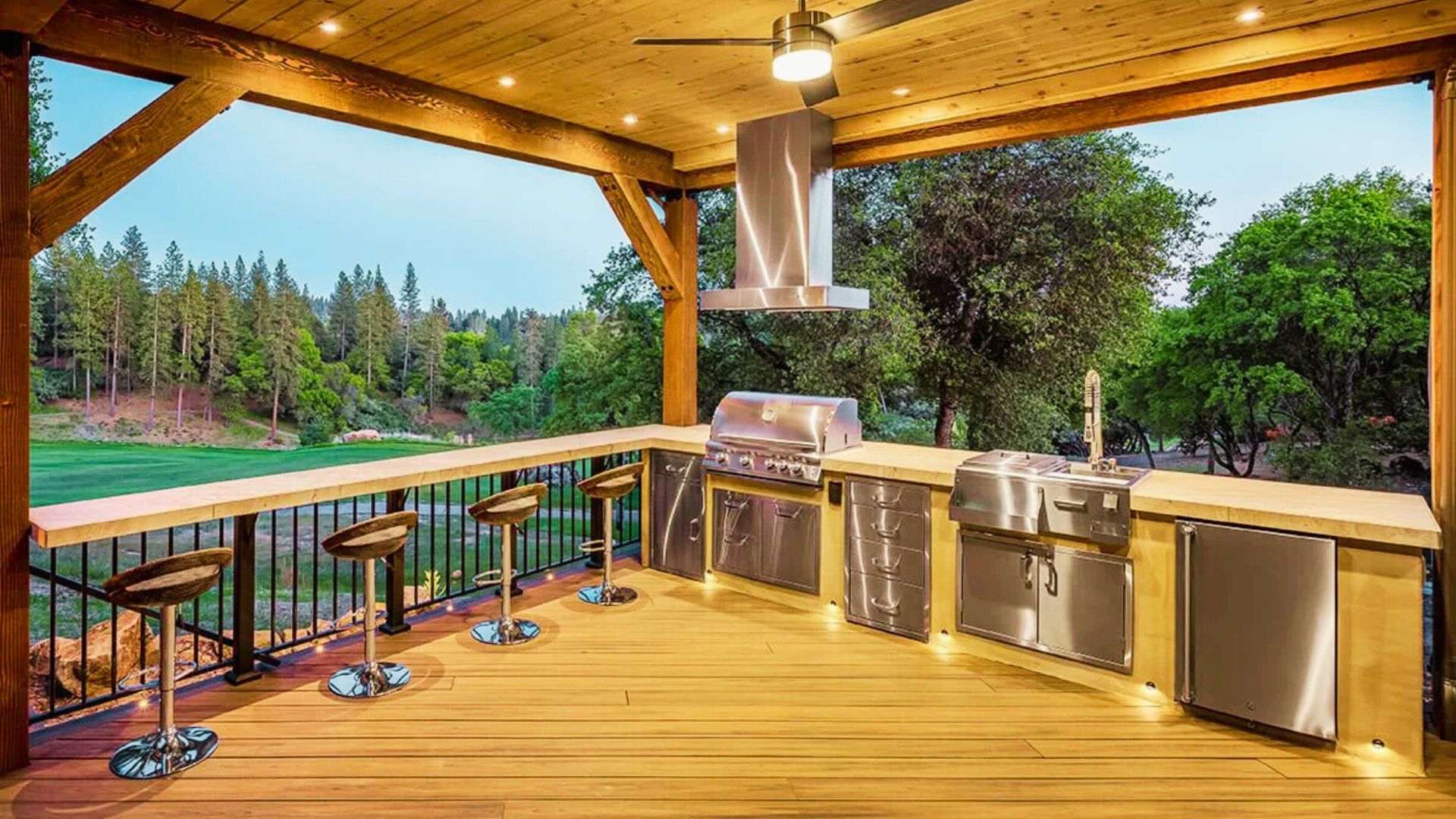 . Outdoor kitchen featuring a grill and bar area, surrounded by greenery and designed for entertaining guests.