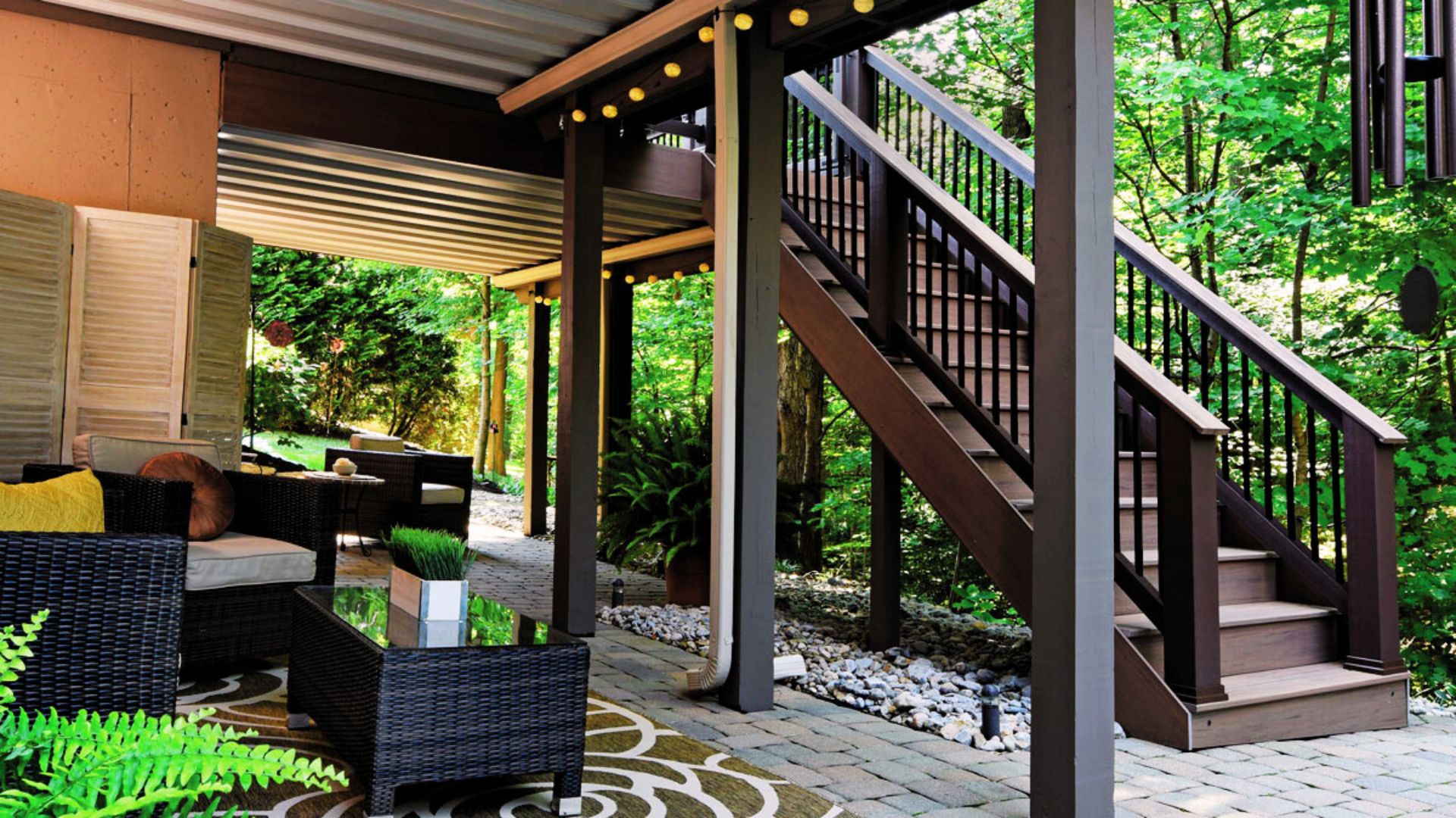A cozy patio with a wicker chair and a staircase, inviting relaxation in a serene outdoor setting.