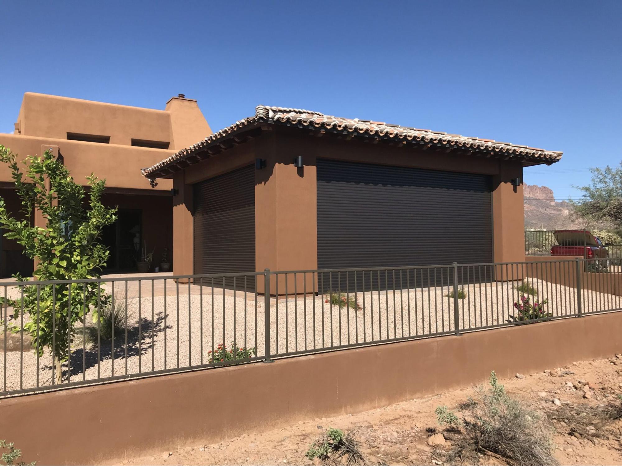 A house featuring a large garage door and a surrounding fence.