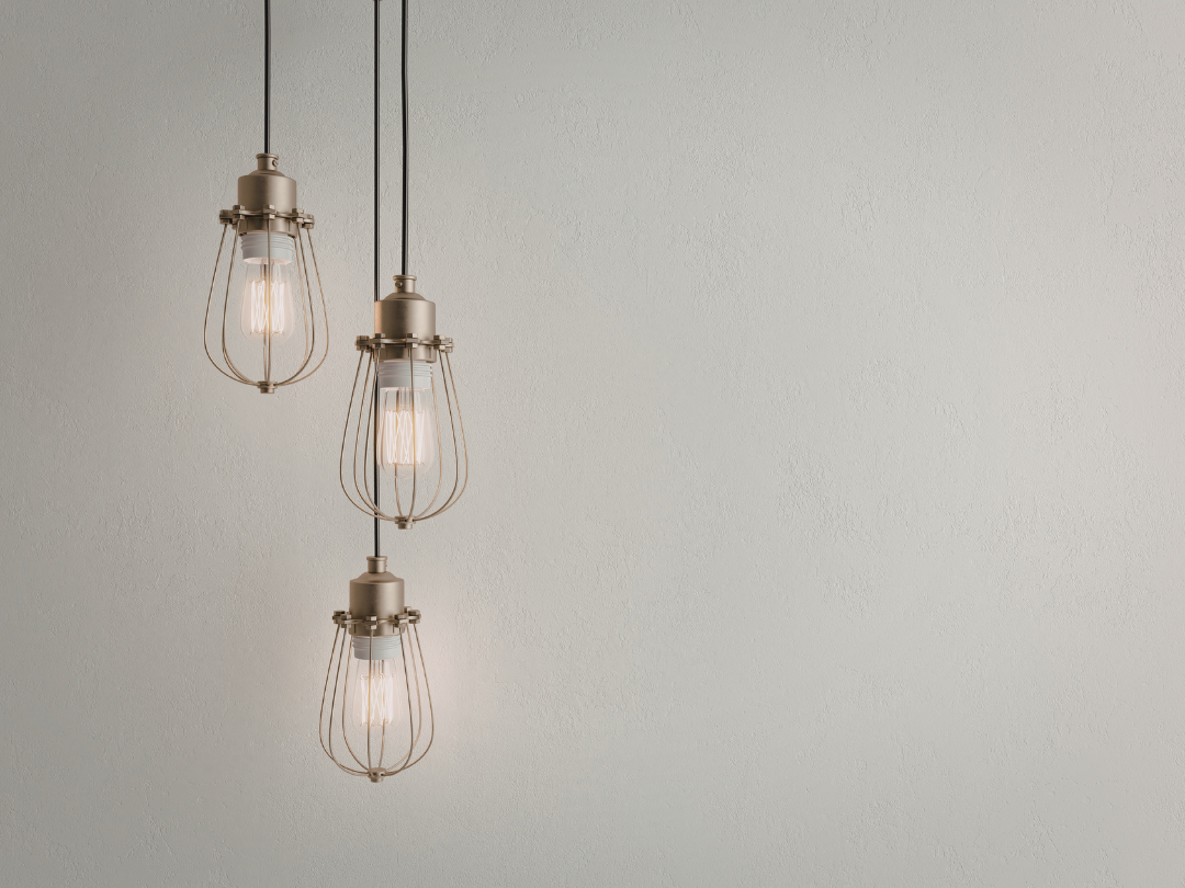 Three vintage-style pendant lights with exposed bulbs hang against a textured white wall, creating a minimalist and warm atmosphere.